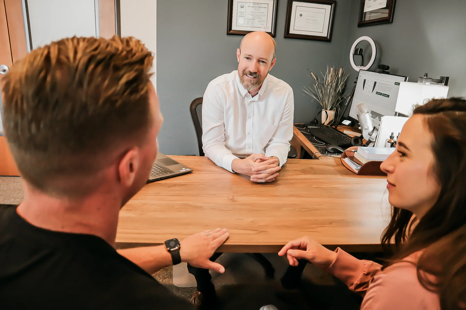Dr. Andrew Rostenberg meeting with a couple across the desk at Red Mountain Natural Medicine in Boise, Idaho — an unhurried, in-person consultation